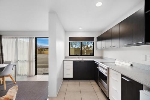 a kitchen with black and white cabinets and a table at Avenue Motel in Alexandra