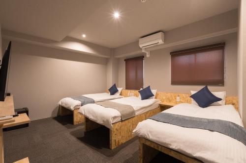 大阪市にある3U NAMBA MINAMI by DOYANENのベッド3台とテレビが備わる部屋