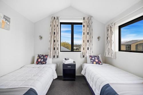 two beds in a room with two windows at Avenue Motel in Alexandra