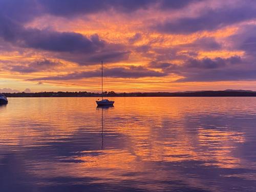 a sailboat in the water at sunset at Niaroo Lakeside in Summerland Point