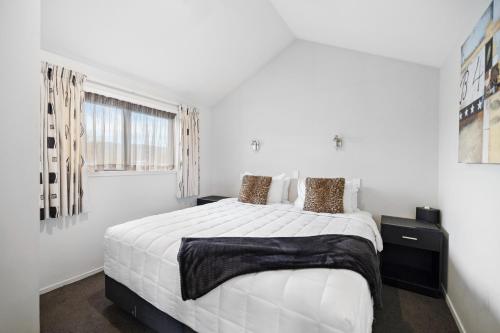 a white bedroom with a large bed and a window at Avenue Motel in Alexandra