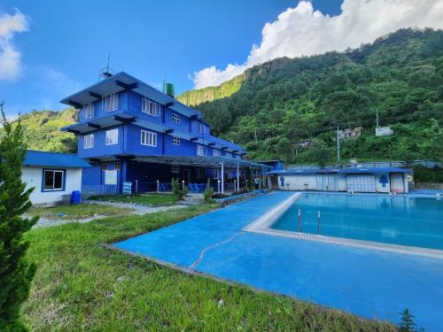 a blue house with a swimming pool in front of a mountain at The Heritage at Lamakhet Hotel in Beni