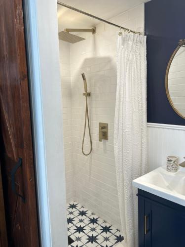 y baño con ducha y azulejos blancos y negros. en Adorable 1 bedroom cottage, en Forest Hills