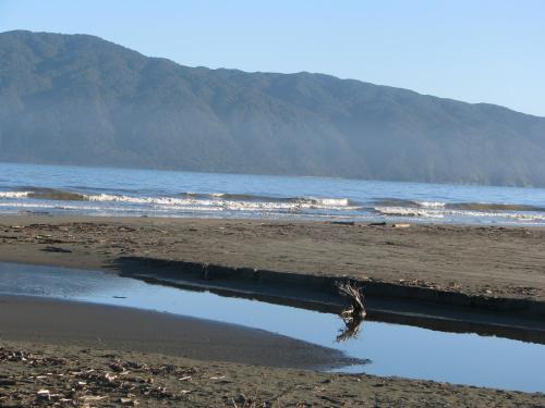 a beach with a body of water and mountains at Top Floor Bed and Breakfast in Paraparaumu Beach