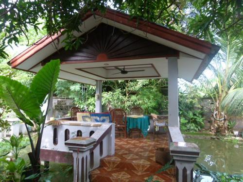 a patio with a pavilion with a table and chairs at Khamphouy Guesthouse in Champasak