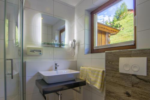 ein Bad mit einem Waschbecken und einem Spiegel in der Unterkunft Gasthof zum Kaiserweg in Schladming