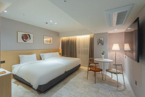 Un dormitorio con una gran cama blanca y una mesa en Asherah Villa d' aqua Hotel en Gimhae