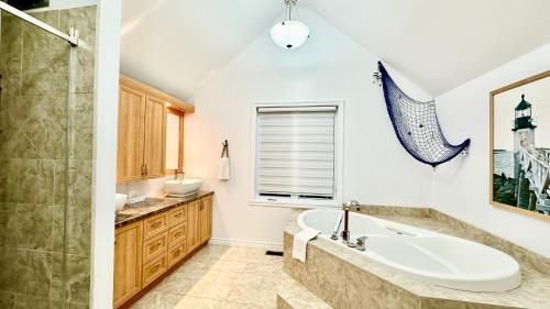 La salle de bains est pourvue d'une baignoire, d'une douche et d'un lavabo. dans l'établissement Chalet Horizon Alpin Spa et Vue sur le Fleuve, aux Éboulements