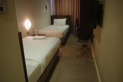 a hotel room with two beds and a television at 101 Hotel Bintulu in Bintulu
