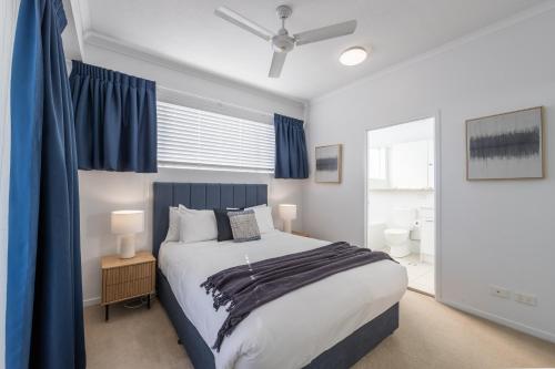 a bedroom with a large bed with blue curtains at Boulevard North Lakes in North Lakes