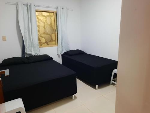2 Betten in einem Zimmer mit Fenster in der Unterkunft Sobrado com Suíte Master em Capitólio Furnas MG in São José da Barra