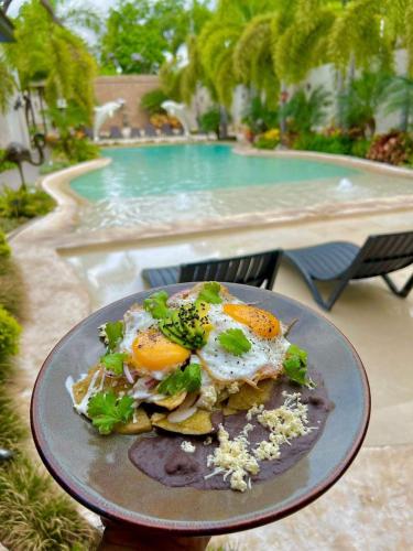 a plate of food with eggs and broccoli in front of a swimming pool at Hotel & Suites Country Valladolid in Valladolid