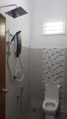 La salle de bains est pourvue de toilettes et d'un sèche-cheveux sur le mur. dans l'établissement Aurora Roomstay, à Kota Bharu