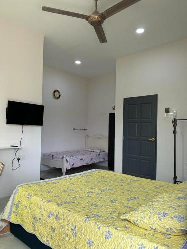 - une chambre avec un lit et un ventilateur de plafond dans l'établissement Aurora Roomstay, à Kota Bharu