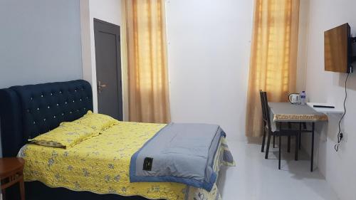 - une chambre avec un lit, une table et un bureau dans l'établissement Aurora Roomstay, à Kota Bharu
