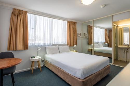 una camera d'albergo con letto, tavolo e scrivania di Port Aloha Motel a Port Macquarie