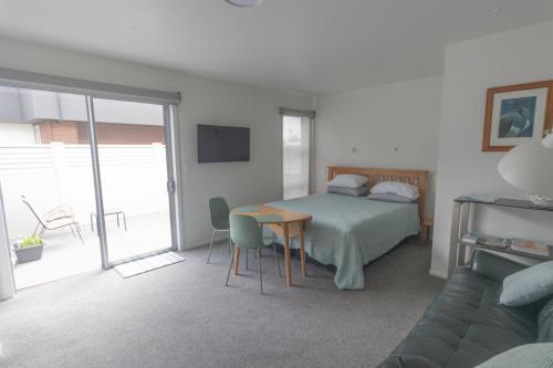 a bedroom with a bed and a table and a couch at Marsden Cove Canal Haven with Spa Pool in One Tree Point