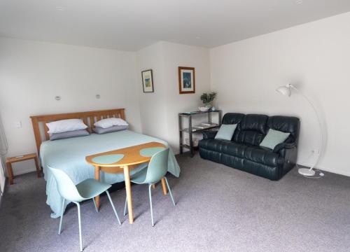 sypialnia z łóżkiem, stołem i kanapą w obiekcie Marsden Cove Canal Haven with Spa Pool w mieście One Tree Point
