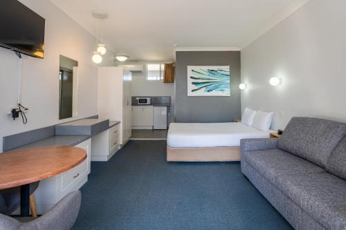 Habitación de hotel con cama y sofá en Port Aloha Motel, en Port Macquarie