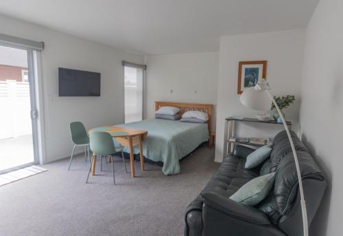 a bedroom with a bed and a couch and a table at Marsden Cove Canal Haven with Spa Pool in One Tree Point