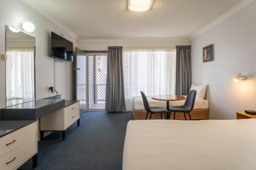 a hotel room with a bed and a table and chairs at Port Aloha Motel in Port Macquarie