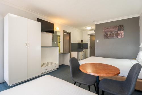 a room with a bed and a table and chairs at Port Aloha Motel in Port Macquarie