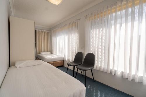 a bedroom with two chairs and a bed and a window at Port Aloha Motel in Port Macquarie