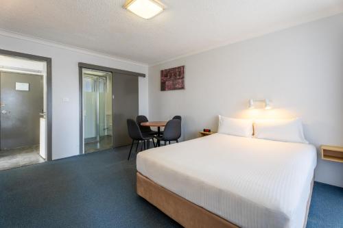 a bedroom with a bed and a table and chairs at Port Aloha Motel in Port Macquarie