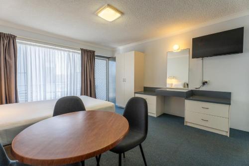a hotel room with a bed and a table and chairs at Port Aloha Motel in Port Macquarie