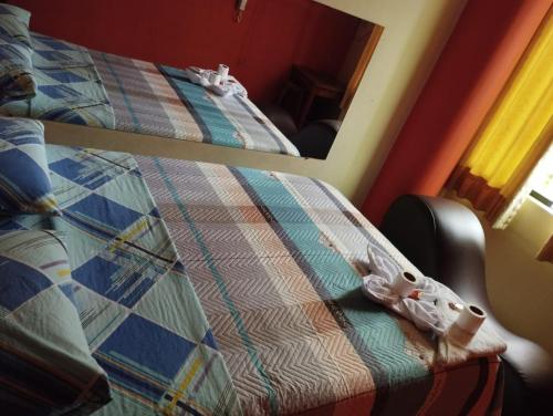 Dormitorio con cama con edredón y espejo en Hostal Corona, en Lima