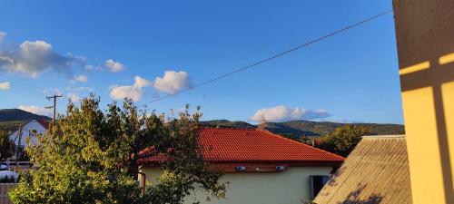a house with a red roof with mountains in the background at Agapé Vendégház in Cserépfalu