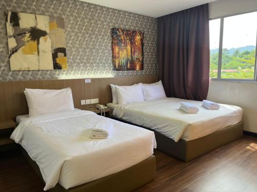 um quarto de hotel com duas camas e uma janela em Hotel DarulMakmur Jerantut em Jerantut