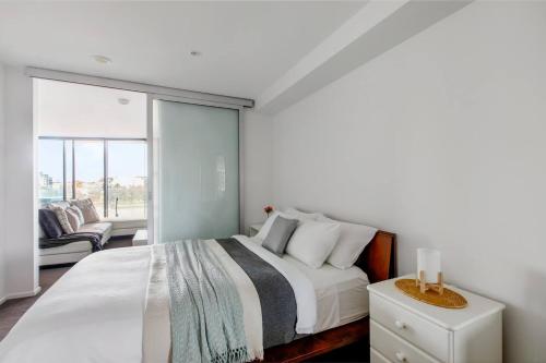 a bedroom with a large white bed and a window at Digital Nomad Dreaming across from Albert Park in Melbourne
