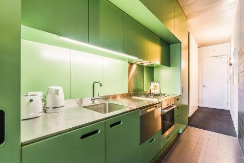 een keuken met groene kasten en een wastafel bij Vibrant Inner-City Living with Luxe Rooftop Pool in Melbourne
