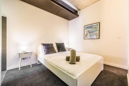 een slaapkamer met een wit bed met een stoel erop bij Vibrant Inner-City Living with Luxe Rooftop Pool in Melbourne