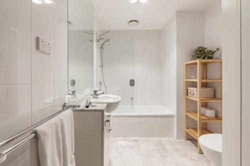 een witte badkamer met een wastafel en een bad bij Cradle the Clouds - Southbank Stay with Parking in Melbourne