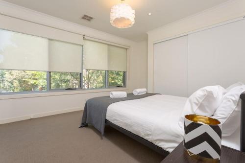 a bedroom with a bed and two windows at Leafy Family Home with Outdoor Dining near CBD in Maribyrnong
