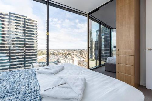 een slaapkamer met een groot bed en grote ramen bij Flagstaff Chic - A Refreshing Balcony Retreat in Melbourne