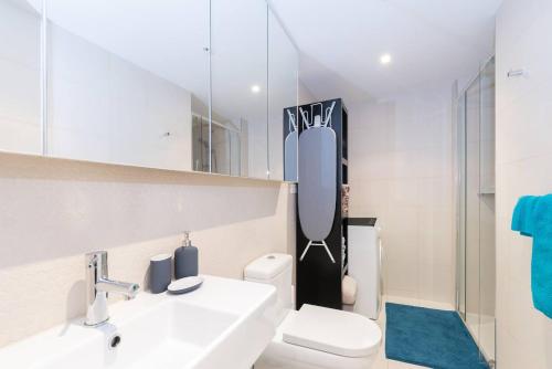 ein Badezimmer mit einem Waschbecken, einem WC und einem Spiegel in der Unterkunft Elevated Elegance in the City's Chic Paris End in Melbourne