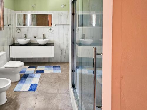 的住宿－The Green Palms Getaway, Palmiste, San Fernando - 6 BR 4 Bath 12 guests，一间带两个水槽和玻璃淋浴间的浴室