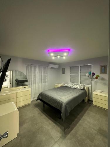1 dormitorio con cama y luz morada en Black Pearl, en Guayama