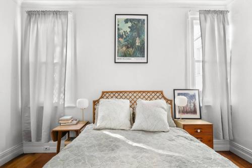 a bedroom with a bed with white walls and windows at Pocket of Petersham - A Stylish Inner-West Retreat in Sydney