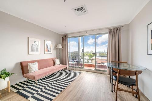 a living room with a pink couch and a glass table at 'Georgina' Mid-Century Modern Poolside Stay in Sydney