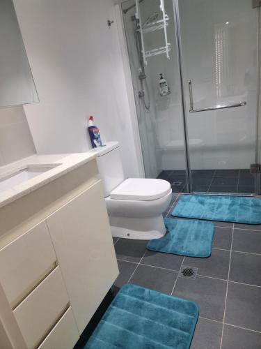 a bathroom with a toilet and blue mats on the floor at Parramatta Shared Apartment in Sydney
