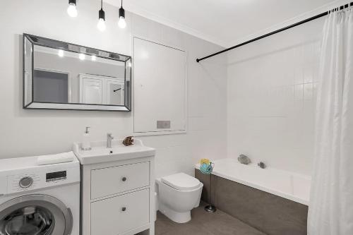 biała łazienka z pralką i umywalką w obiekcie 'Georgina' Mid-Century Modern Poolside Stay w mieście Sydney