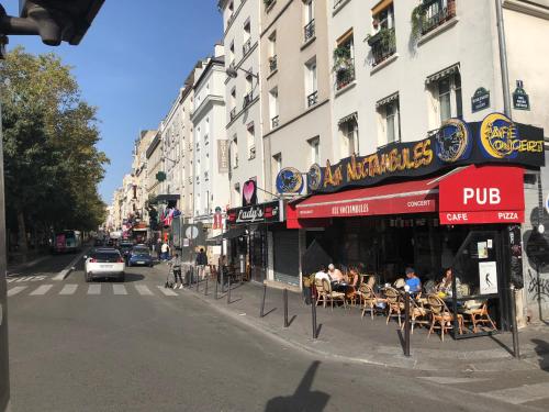 a street with people sitting at tables outside a restaurant at Studio Pigalle de 25 m2 - 2 lits simples type gigogne pour 2 personnes - Quartier HyperTouristique - 3 minutes de la station Métro Pigalle ,Petit Train vers la butte Montmartre - Cabaret Moulin Rouge -Restaurants Bouillon Pigalle,Berliner Pigalle in Paris