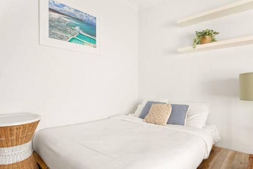 a white bed in a white room with at A Cosy Scandi-Style Studio on Bondi Beach in Sydney