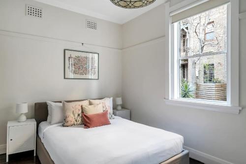 een witte slaapkamer met een bed en een raam bij Coogee Classic - Coastal Gem Close to Beach in Sydney