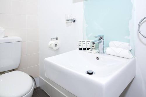 a white bathroom with a sink and a toilet at Courtyard Esperanza - Sunny Heritage Chic in Sydney