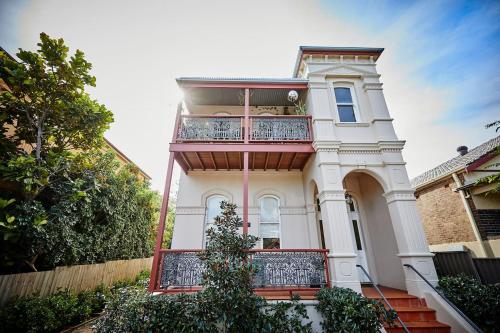 a large white house with a balcony on it at Esperanza Gardens - A Stylish Victorian Studio in Sydney
